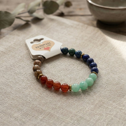 Multicolored beaded bracelet on a beige surface with a 'Handmade with Love' tag.