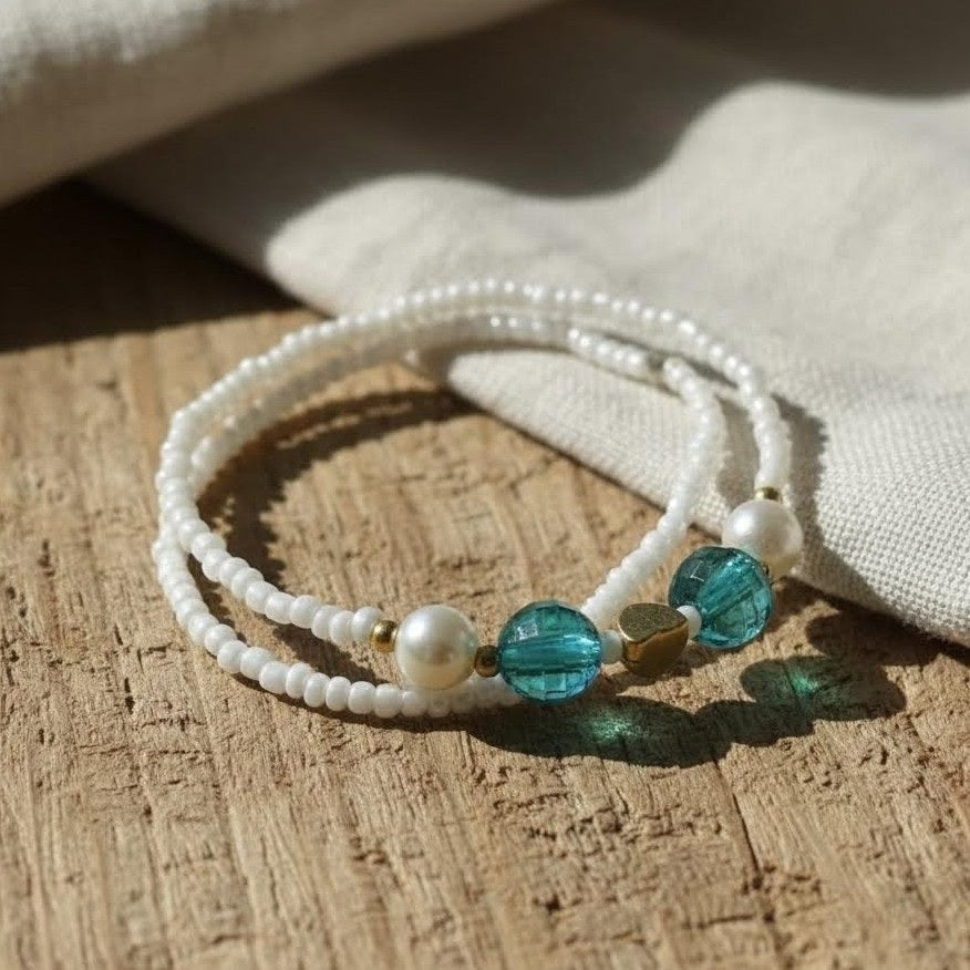 White beaded bracelet with blue and gold accents on a wooden surface