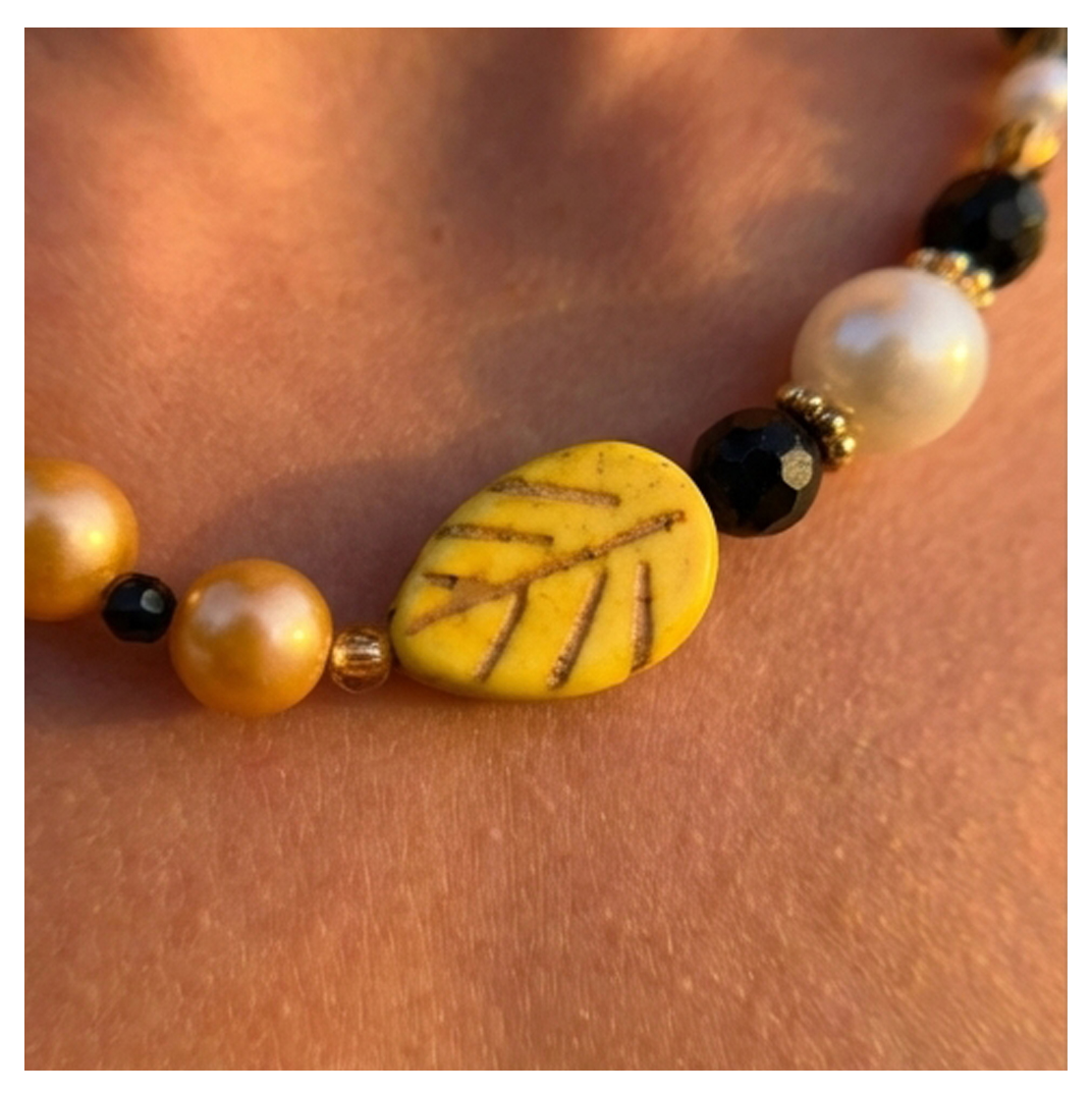Necklace with yellow leaf bead on a skin background