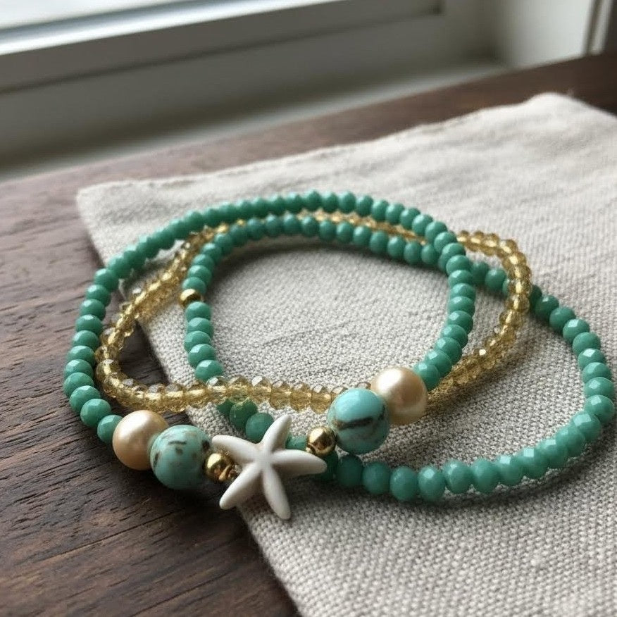 Set of turquoise and gold beaded bracelets with a starfish charm on a textured surface.