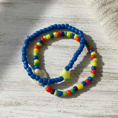 Two colorful beaded bracelets on a light wooden surface