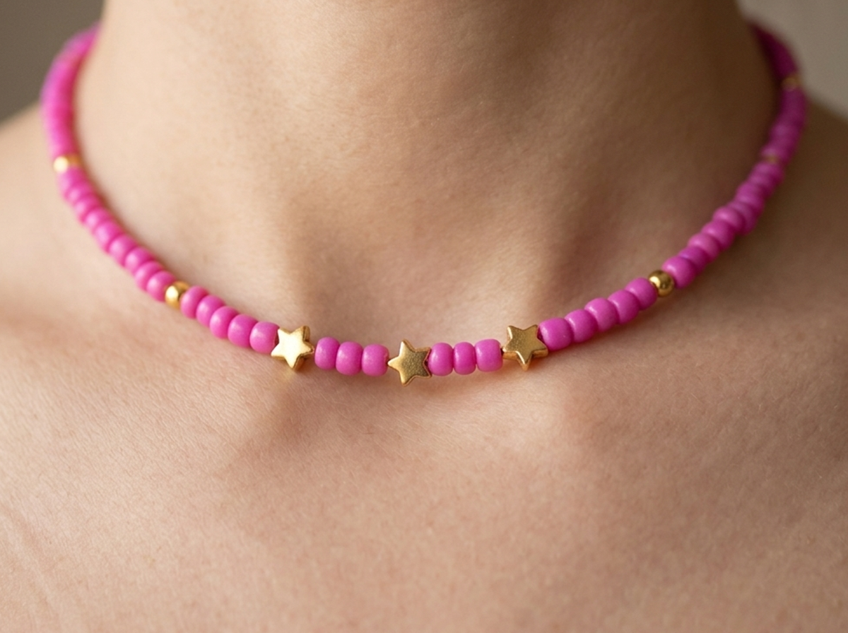 Pink beaded necklace with gold star accents on a person's neck