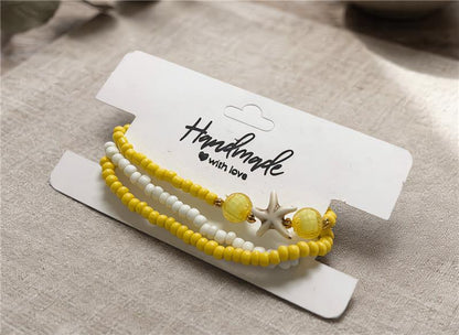 Yellow and white beaded bracelet on a 'Handmade with Love' card on a beige fabric background