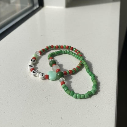Beaded bracelet with green, red, and white beads on a light surface