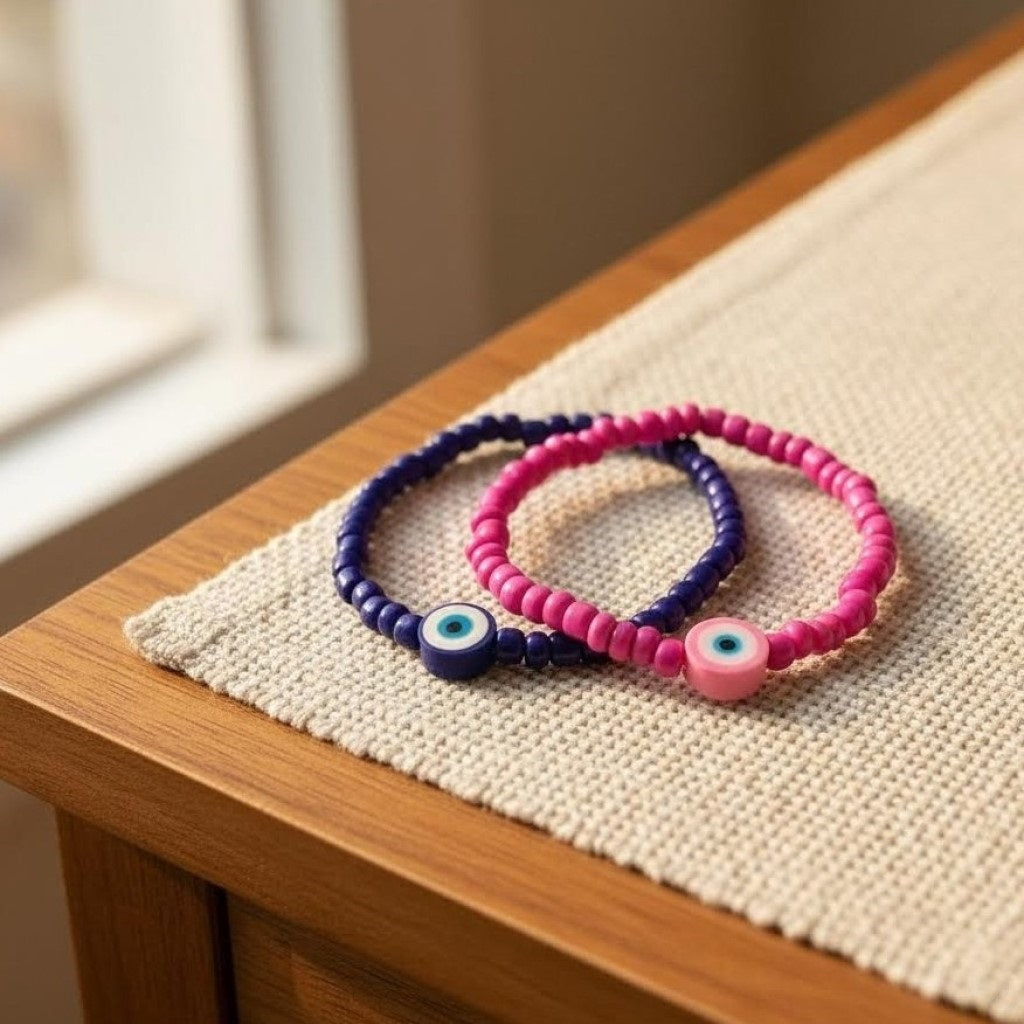 Two beaded bracelets, one pink and one blue, on a wooden surface with a neutral background.