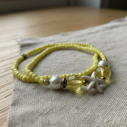 Yellow beaded bracelet with starfish charm on a textured fabric surface