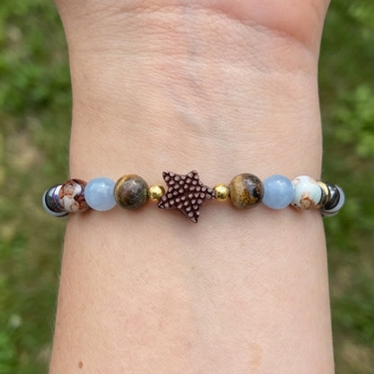 Bracelet with beads and a leaf charm on a wrist against a blurred green background