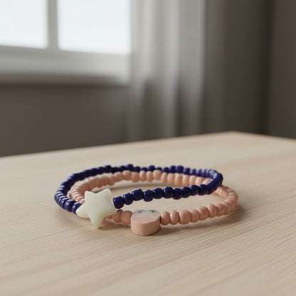 Two beaded bracelets with star and heart charms on a wooden surface.
