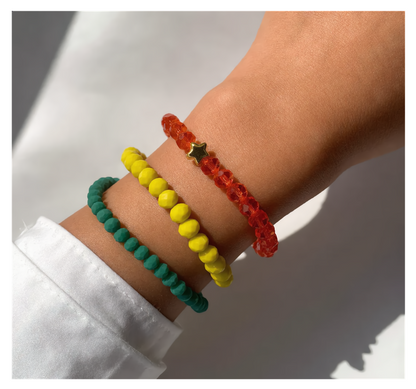 Close-up of a wrist wearing three colorful beaded bracelets on a neutral background