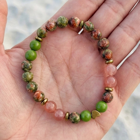 Beaded bracelet with green and pink beads on a hand against a blurred natural background