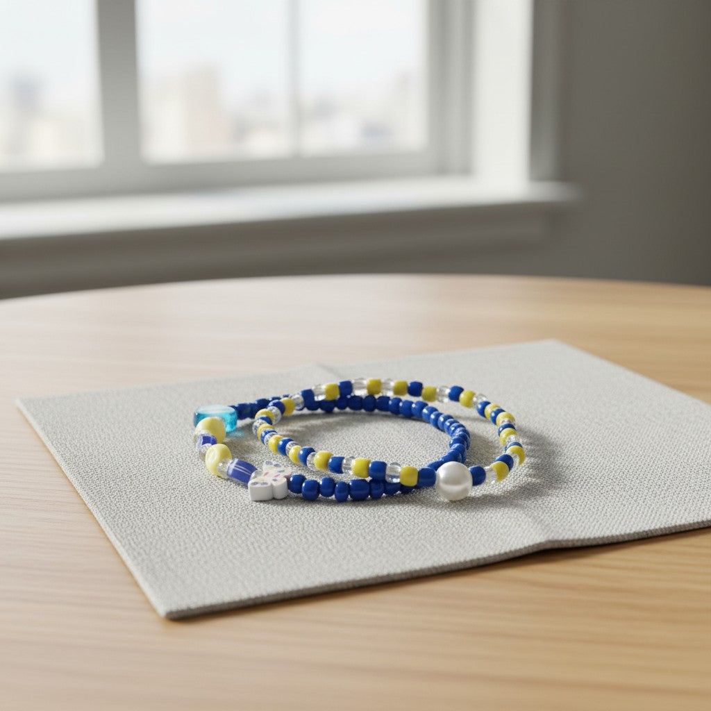 Two beaded bracelets on a gray mat with a window in the background