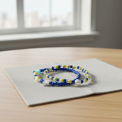 Two beaded bracelets on a gray mat with a window in the background