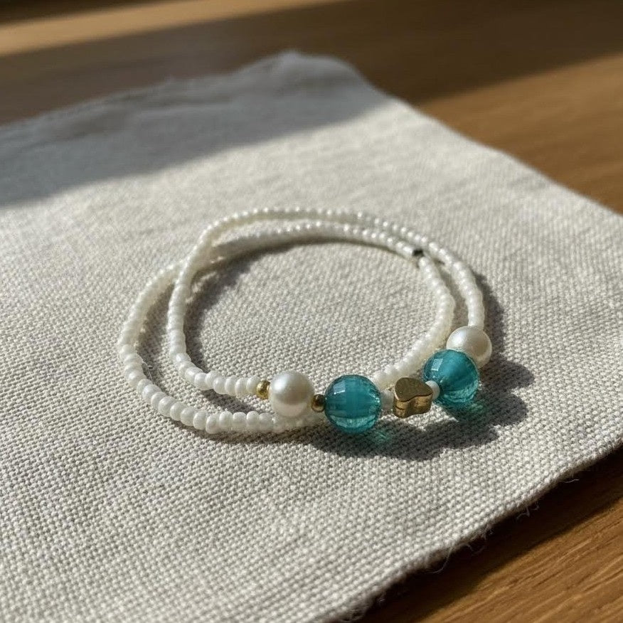 Beaded bracelet with turquoise beads on a textured fabric surface